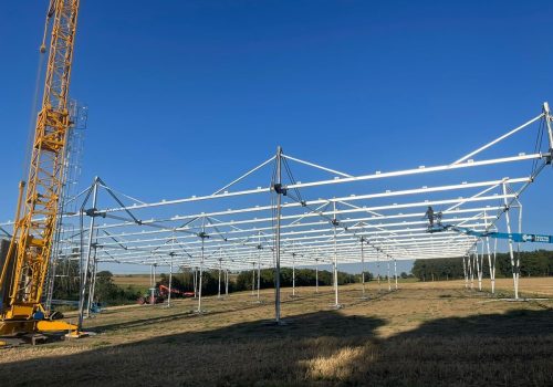 Montage der Unterkonstruktion einer Agri-PV-Anlage mit Kran auf freiem Feld