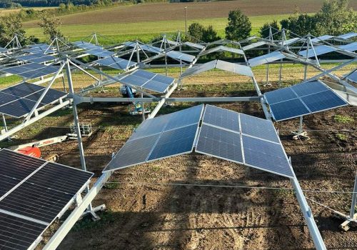 Reihen von Solarmodulen einer Agri-PV-Anlage über landwirtschaftlicher Fläche, Blick von erhöhter Position